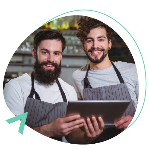 dos empleados de un restaurante sonriendo mientras utilizan una tablet