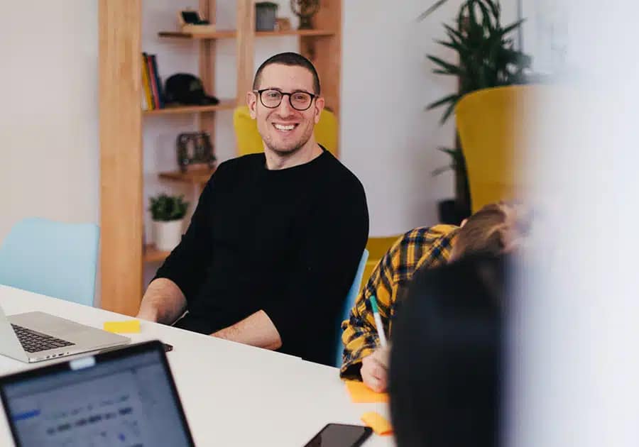 chico joven sonriendo sentado en una mesa de oficina