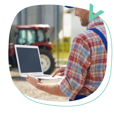 hombre sosteniendo un ordenador portatil con un tractor de fondo